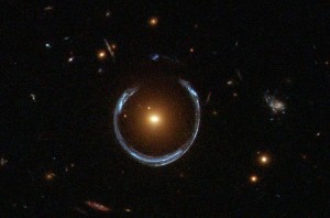 Esta imagen muestra el efecto de la lente gravitacional. La galaxia roja (en el centro) distorsiona la luz de una galaxia azul muchísimo más distante. Crédito: ESA/Hubble & NASA