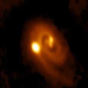 Imagen capturada por el telescopio ALMA del sistema L1448 IRS3B, con dos estrellas jóvenes en el centro y una tercera en la distancia. Crédito: Bill Saxton, ALMA (ESO/NAOJ/NRAO), NRAO/AUI/NSF